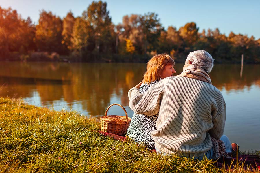 Contact - Older Couple Relaxing At The Lake During The Fall